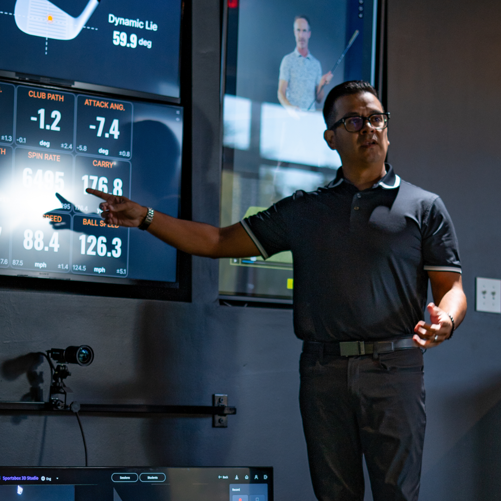 Golf instructor demonstrating swing analysis with TrackMan data during a lesson at Studio Golf El Paso.