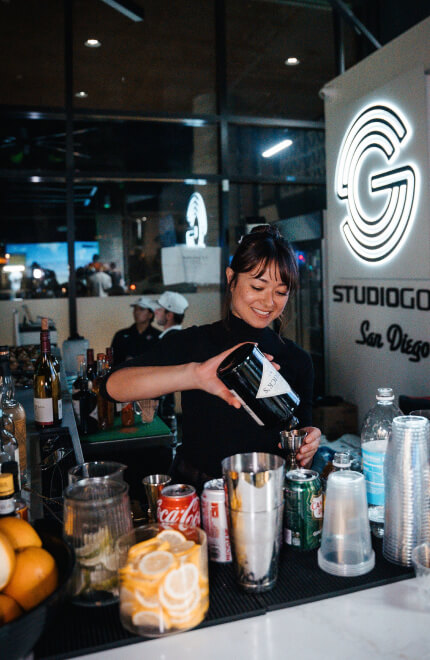 Bartender serving drinks at the Studio Golf bar with a display of fresh ingredients.