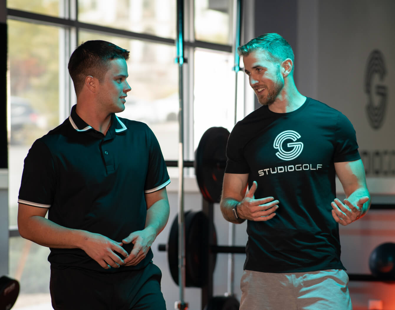 Two golfers discussing mobility assessment with a Studio Golf fitness coach.