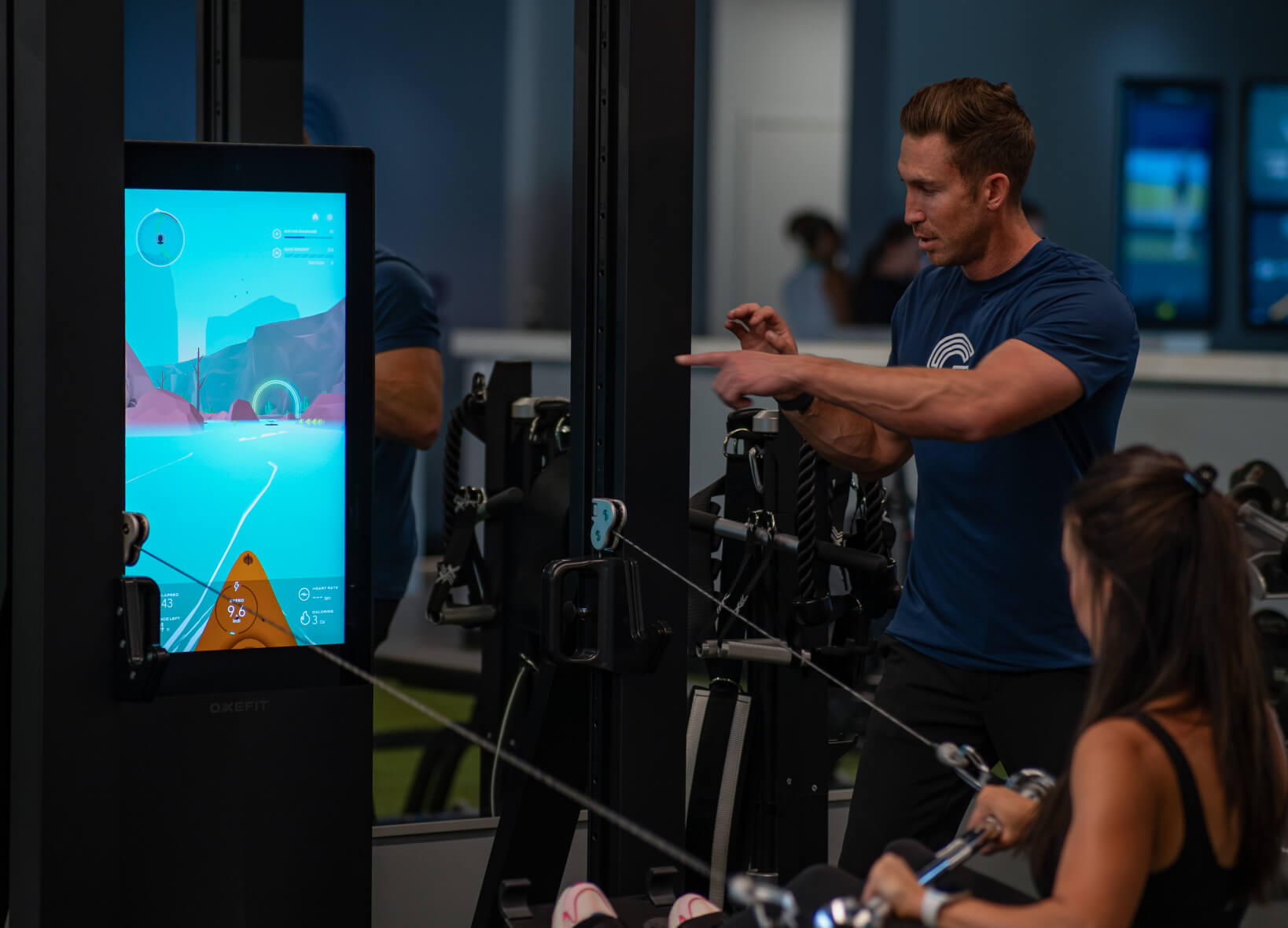 Studio Golf trainer guiding a member using OxeFit Smart Gym technology.