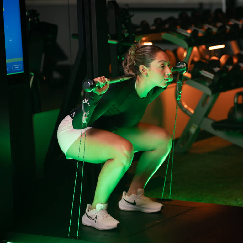Athlete performing a squat exercise with barbell during a golf fitness session at Studio Golf South Bay.