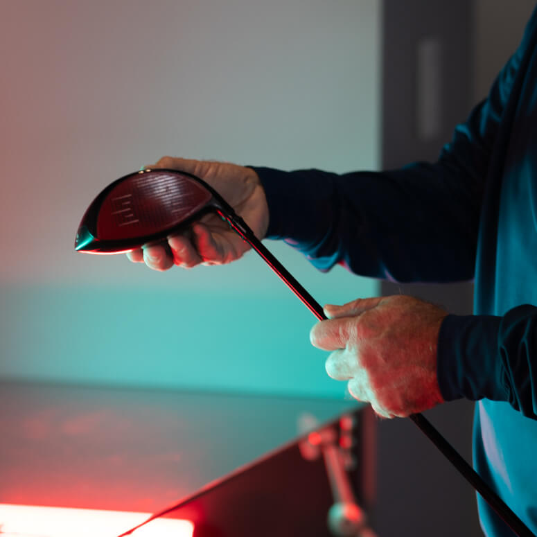 Close-up of a club fitter adjusting a driver head during a custom fitting session at Studio Golf San Diego.